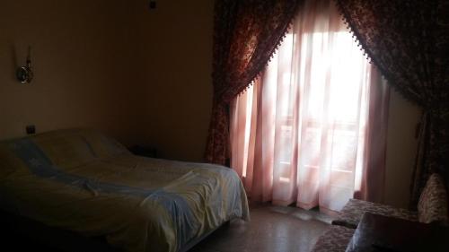 a bedroom with a bed and a window with curtains at Hotel les palmiers in Agadir