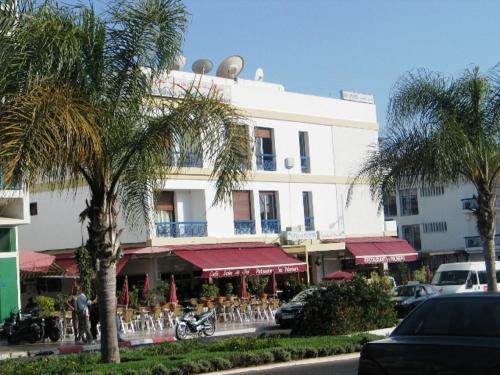 a large white building with palm trees in front of it at Hotel les palmiers in Agadir