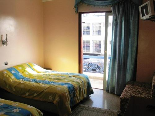una camera con due letti e una porta per una finestra di Hotel les palmiers ad Agadir