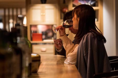 a woman sitting at a bar drinking a glass of wine at PROSTYLE RYOKAN TOKYO ASAKUSA in Tokyo
