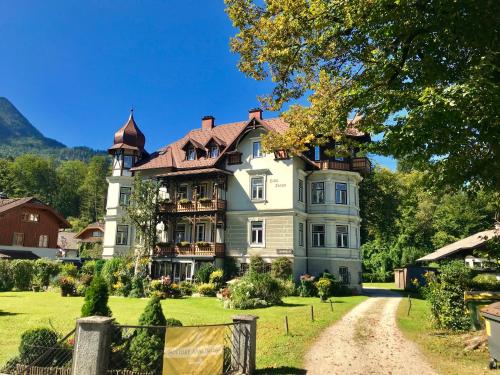 ein großes Haus mit einem Turm auf einem grünen Rasen in der Unterkunft Villa Traun in Bad Ischl