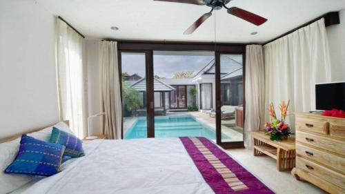 a bedroom with a large bed and a swimming pool at Villa Hibiscus in Sanur