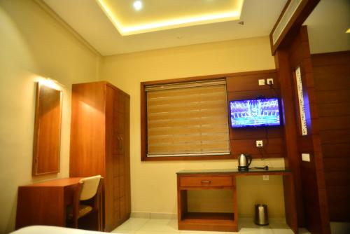 a room with a kitchen with a television in it at Hotel Priya in Kottakkal