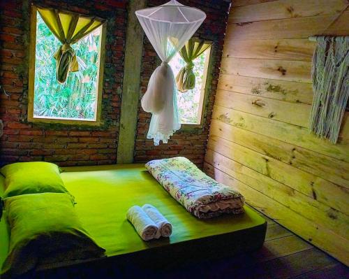 Cette chambre comprend un lit vert et 2 serviettes. dans l'établissement Ne Pakku Manja Family Home, à Rantepao