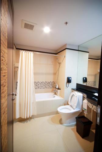 a bathroom with a toilet and a bath tub at Tara Mantra Cha-Am Resort in Cha Am