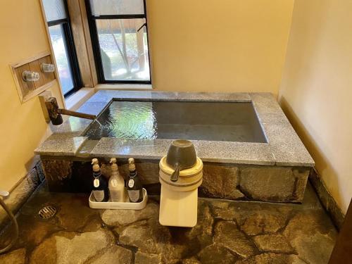 eine Whirlpool-Badewanne in einem Zimmer mit einigen Flaschen in der Unterkunft Shikinosato Hanamura in Minamioguni