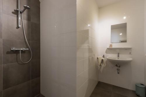 ein weißes Bad mit einer Dusche und einem Waschbecken in der Unterkunft Appartement - Kaapduinseweg 13 Dishoek M Luxe 6 personen in Koudekerke