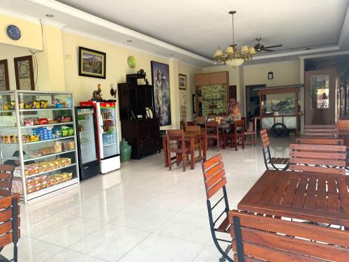a restaurant with benches and a table and a refrigerator at De Gadri Ndalem Yogyakarta in Bantul