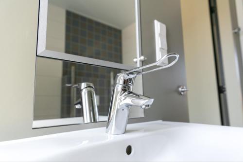 a bathroom sink with a faucet and a mirror at 6p Luxe bungalow met serre in 's-Gravenzande