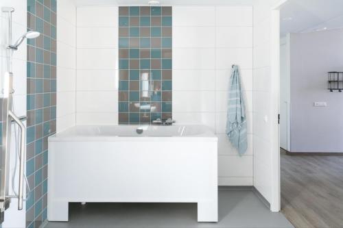een badkamer met een wit bad en een wastafel bij 8p Luxe bungalow met serre in 's-Gravenzande