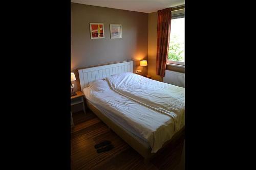 a bedroom with a bed and a window at Bungalow 14 personen in s-Gravenzande