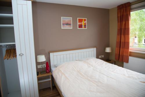 um quarto com uma cama branca e uma janela em Bungalow 6 personen em s-Gravenzande