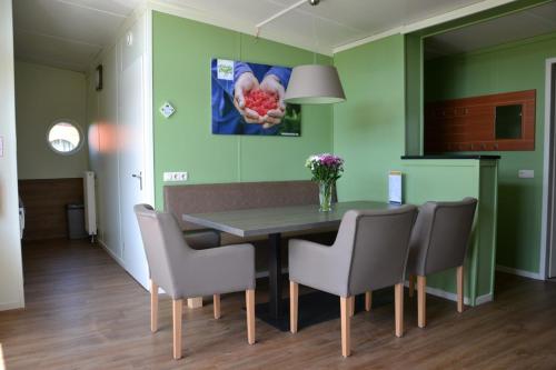 ein Esszimmer mit grünen Wänden sowie einem Tisch und Stühlen in der Unterkunft Bungalow 8 personen in s-Gravenzande