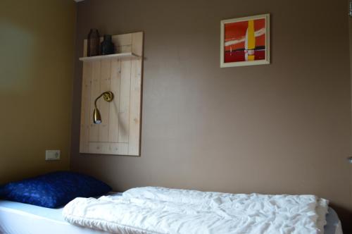 ein Schlafzimmer mit einem weißen Bett und einem blauen Kissen in der Unterkunft Bungalow 8 personen in s-Gravenzande