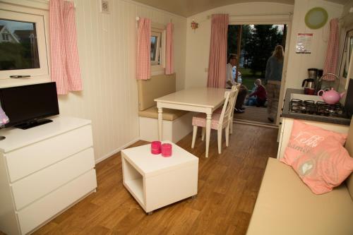 a small room with a table and a kitchen at Pipowagen op het park in s-Gravenzande