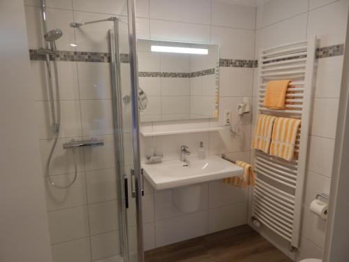 a bathroom with a sink and a shower at Hotel garni Haaster Krug Otte in Großenkneten