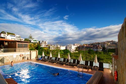 a pool at a hotel with chairs and umbrellas at Hapimag Ferienwohnungen Puerto de la Cruz in Puerto de la Cruz