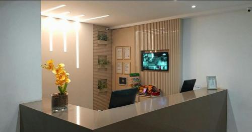 a reception desk in an office with a vase of flowers at Hotel Conceição in Linhares