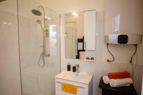 a white bathroom with a shower and a sink at Csilla Home Apartman in Miskolc