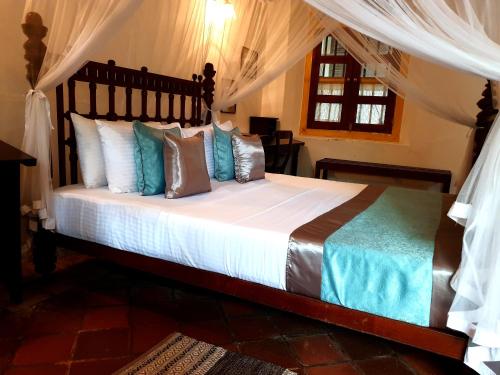 a bedroom with a bed with a canopy at Nooit Gedacht Heritage Hotel (Original Dutch Governors House) in Unawatuna