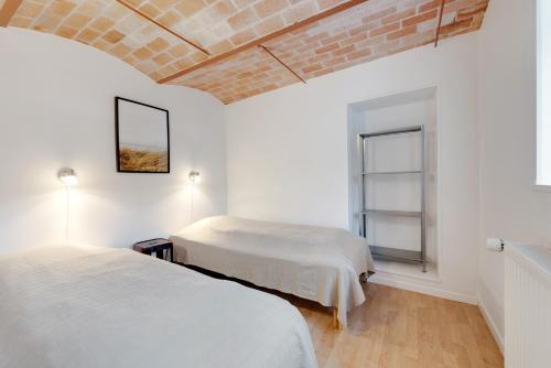 two beds in a white room with a brick wall at Adventure Park Apartments in Ringkøbing