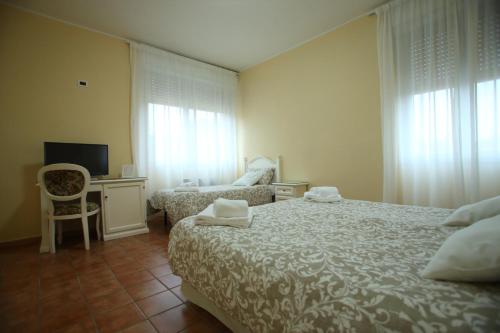 a bedroom with a bed and a chair and a desk at Hotel Villa Romana in Piazza Armerina