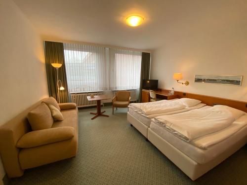 a bedroom with a bed and a chair and a couch at Hotel Flensburger Hof in Flensburg