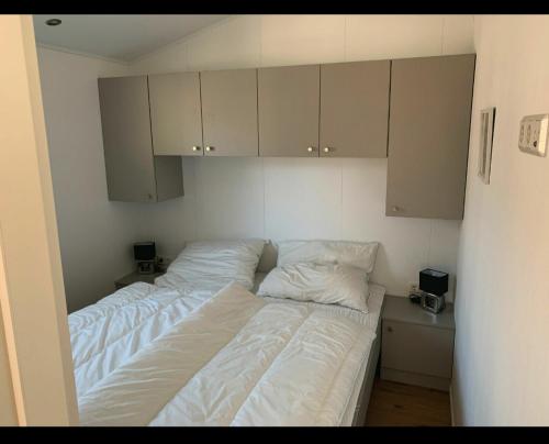 1 dormitorio con 2 camas, sábanas blancas y armarios en Beach Chalet SunHus - modernes Chalet in Ostseenähe, en Scharbeutz