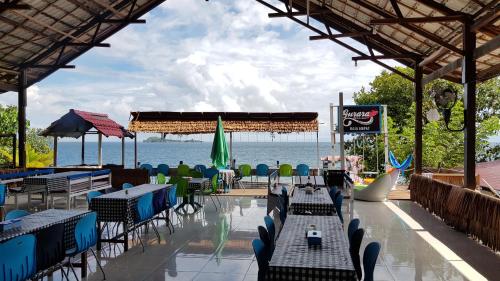 a restaurant with tables and chairs and the ocean at Gurara Dive Resort in Tapokreng