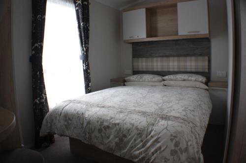 a bedroom with a bed with a white comforter and a window at The Royal Clovelly caravan with sea views in Bideford
