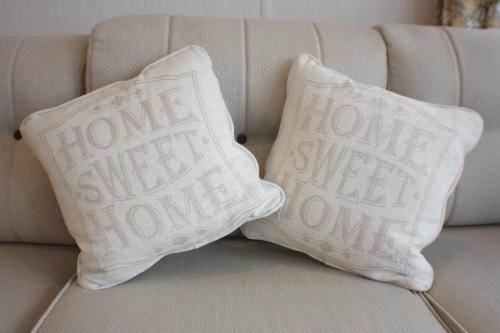 two pillows on a couch with the words home sweet home at The Royal Clovelly caravan with sea views in Bideford