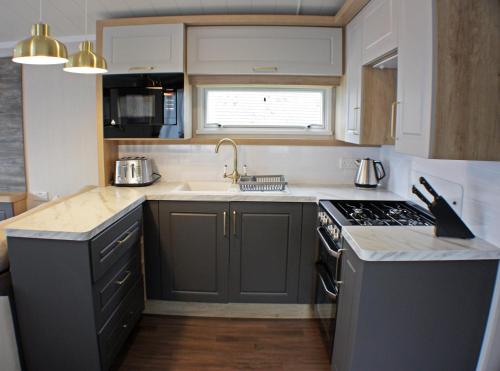 a kitchen with a sink and a stove top oven at The Royal Clovelly caravan with sea views in Bideford