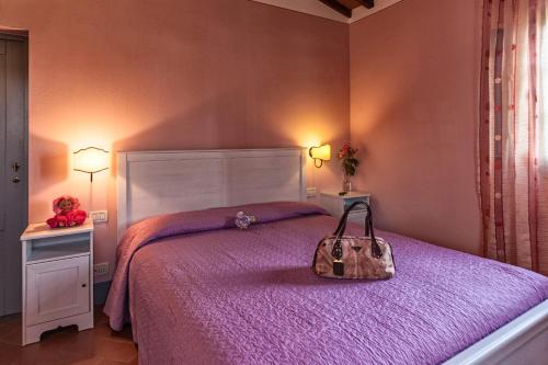 a bedroom with a purple bed with a purse on it at Agriturismo Relais Campiglioni in Montevarchi