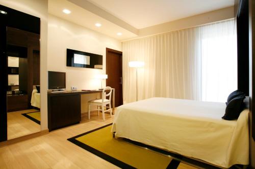 a bedroom with a bed and a desk with a computer at Hotel Bienestar Moaña in Moaña