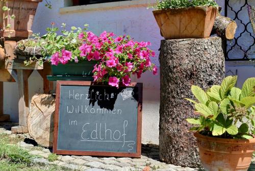 a sign with flowers on it next to some potted plants at Zum Edlhof in Obernzell