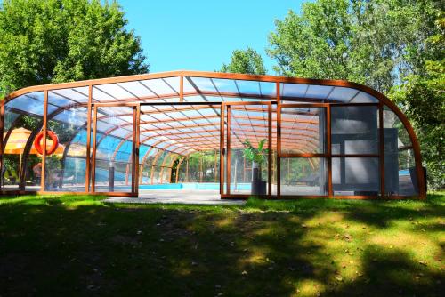 einen Pavillon mit einem Glasgebäude in einem Park in der Unterkunft Geréby Kúria Hotel és Lovasudvar in Lajosmizse