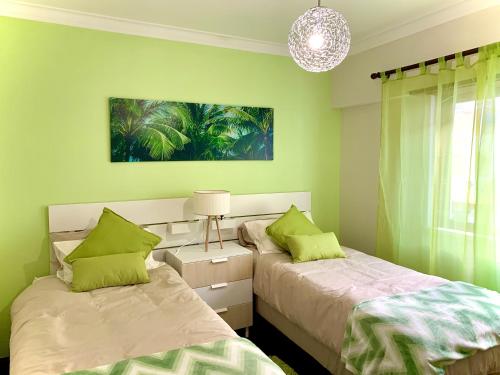 two beds in a room with green walls at Cascais Spacious Getaway in Cascais