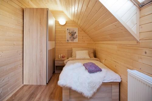 een kleine kamer met een bed in een houten hut bij Wiśniewski Apartamenty pod Szczyrkiem in Szczyrk