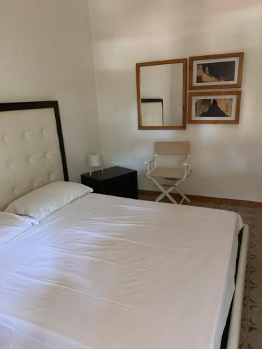 a bedroom with a white bed and a chair at Matteo's home in Donnalucata