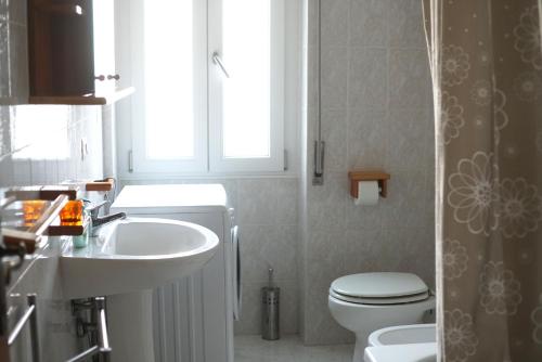 a bathroom with a sink and a toilet and a window at White Sand Alghero in Alghero