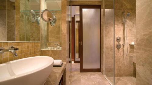 a bathroom with a tub and a sink and a shower at Wyndham Grand Tianjin Jingjin City in Tianjin