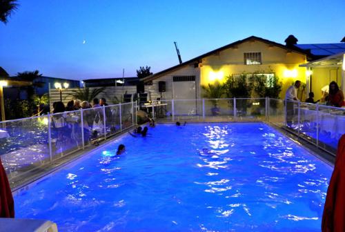 a swimming pool with people in the water at night at Locanda del Lupo in Faenza