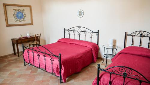 a bedroom with two beds with red sheets and a table at B&B S. Teresa in Altamura