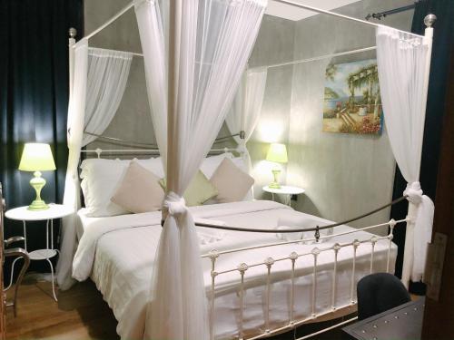 a bedroom with a white canopy bed with curtains at House Of Passion Amphawa in Amphawa