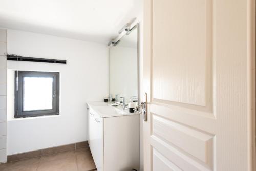a white bathroom with a door and a sink at chez nico in Bédoin