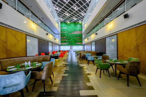 um restaurante com mesas e cadeiras e uma parede verde em Essentia Manipal Inn em Udupi