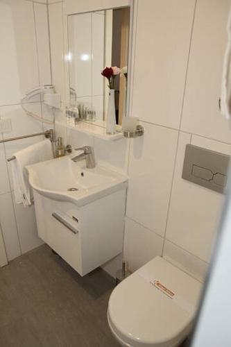 a white bathroom with a toilet and a sink at Kispet Deluxe Hotels&Suites in Oberhausen