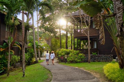 Rebak Island Resort & Marina, Langkawi في بانتايْ سينانج: رجل وامرأة يسيران في طريق امام المنزل