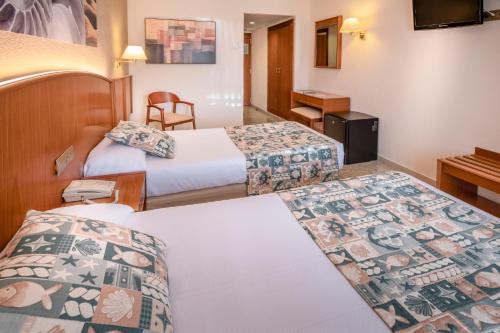 a hotel room with two beds and a desk at GHT Oasis Park & Spa in Lloret de Mar