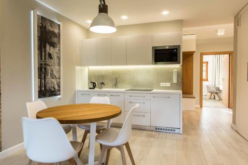 a kitchen with a wooden table and white chairs at Royal Hill Residence in Zakopane